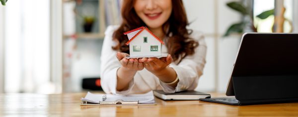 Close up of woman hands holding home model, Real estate brokerag